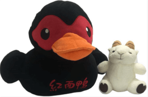 一隻黑色橡皮鴨和一隻中國毛絨玩具。