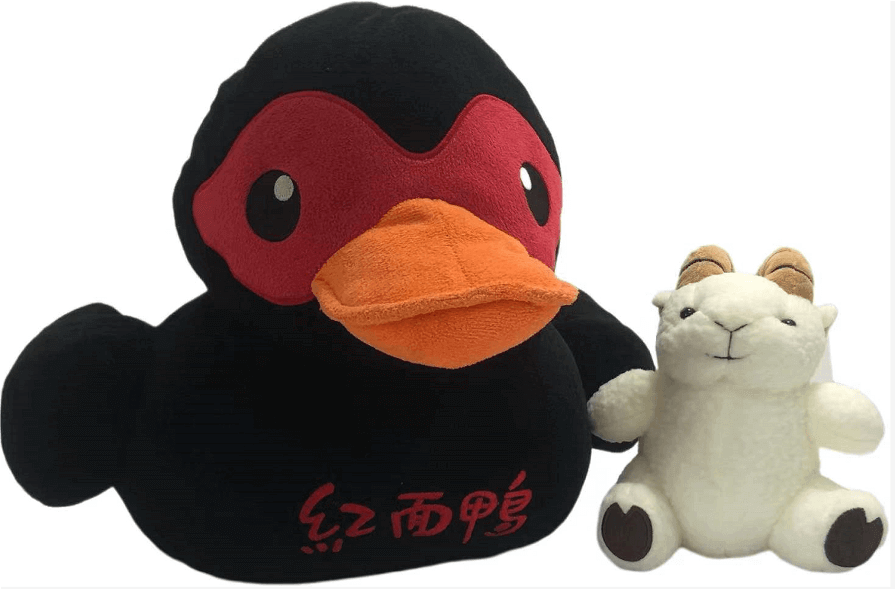 一隻黑色橡皮鴨和一隻中國毛絨玩具。